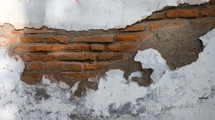 Peeling white painted wall on classic red brick surface, aged grunge look with decay patterns, high...