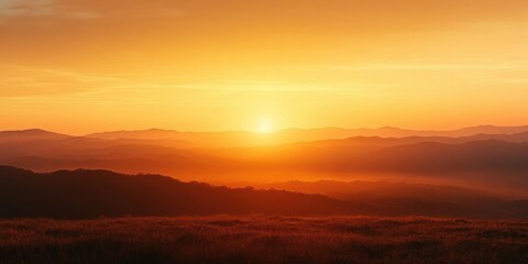 Vibrant orange sunrise over rolling hills and distant mountain ranges with a peaceful and warm atmosphere