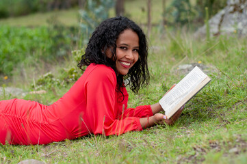 Young woman reading a book lying on grass in a park