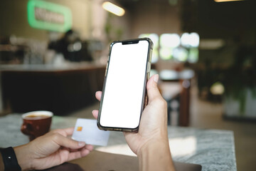 A person holding a smartphone with a blank white screen and a credit card, ready for online shopping or mobile payment. E-commerce mockup concept.