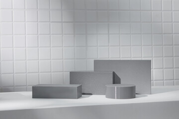 Layered grey blocks including cylinders and rectangles arranged across curved shadows. Subtle...
