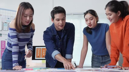 Young asian uiux designers collaborating closely while developing mobile application prototype, engaged in strategic planning and innovative design process within modern creative workspace - Powered by Adobe
