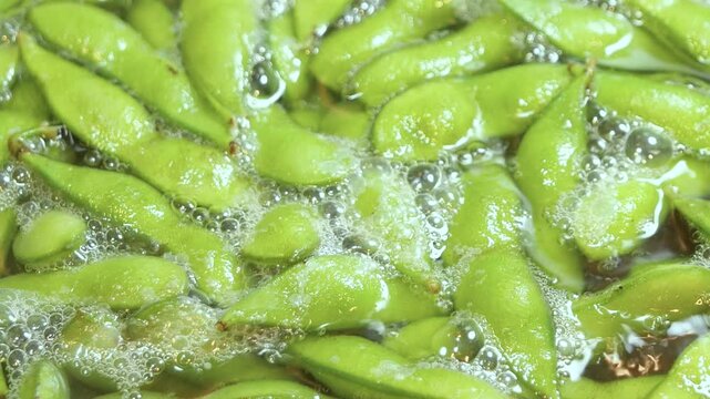 夏野菜の枝豆をお湯で茹でている動画。クローズアップ。左から右へ。
