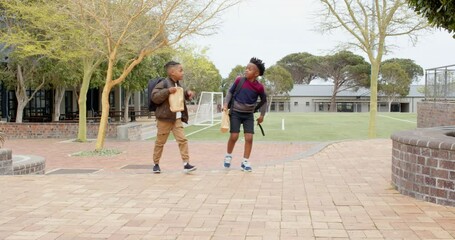 Walking with backpacks and lunch bags, multiracial boys chatting happily at school - Powered by Adobe