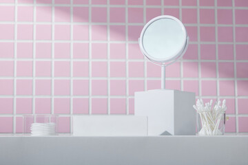 White podiums arranged below pink mosaic tiles with vanity mirror and cotton swabs. A soft,...
