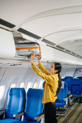 Attractive Asian female passenger of airplane sitting in comfortable seat while working laptop and...