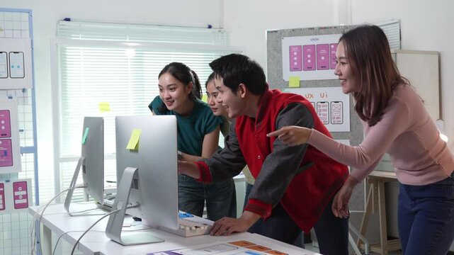 Professional design team celebrating successful project completion, expressing shared excitement and joy while gathered around computer in modern office workspace