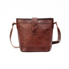 Beautiful dark brown leather shoulder bag with embossed decoration for women isolated on white...