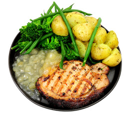 Pepper crusted pork loin steak meal with new potatoes and apple sauce isolated on a white background
