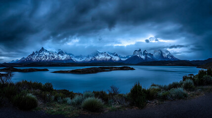 Dramatic mountain landscape with deep blue lake reflecting snow peaks under stormy clouds, conveying majestic wilderness and solitude, space for text on left