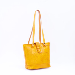Beautiful yellow leather shoulder bag with embossed decoration for women isolated on white...