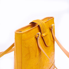 Beautiful yellow leather shoulder bag with embossed decoration for women isolated on white...