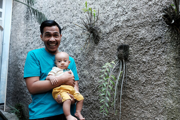 A Southeast asian father playing with baby boy in the home garden, doing everything together. Happy family 