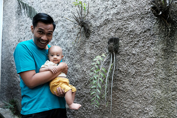 A Southeast asian father playing with baby boy in the home garden, doing everything together. Happy family 