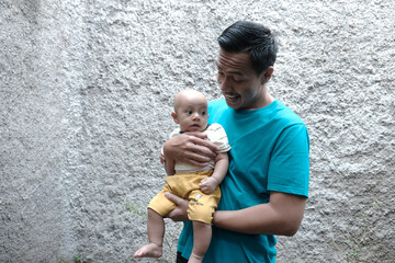 A Southeast asian father playing with baby boy in the home garden, doing everything together. Happy family 