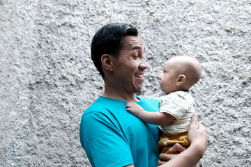 A Southeast asian father playing with baby boy in the home garden, doing everything together. Happy family 