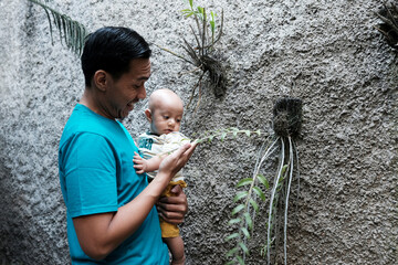 A Southeast asian father playing with baby boy in the home garden, doing everything together. Happy family 