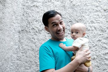 A Southeast asian father playing with baby boy in the home garden, doing everything together. Happy family 