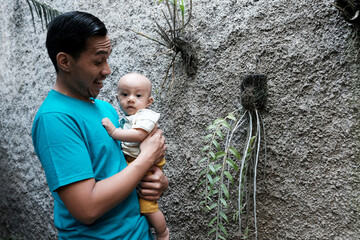 A Southeast asian father playing with baby boy in the home garden, doing everything together. Happy family 