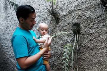 A Southeast asian father playing with baby boy in the home garden, doing everything together. Happy family 