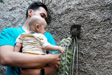 A Southeast asian father playing with baby boy in the home garden, doing everything together. Happy family 