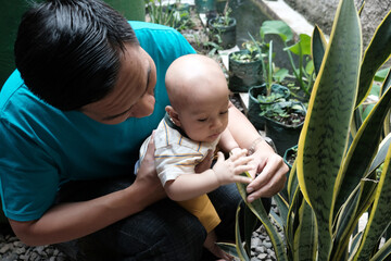A Southeast asian father playing with baby boy in the home garden, doing everything together. Happy family 
