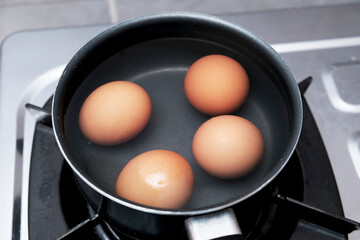A pan with some boiling eggs on a stove. Chicken eggs in boiling water. Cooking process.