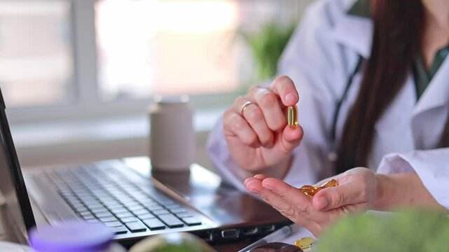 Doctor shows transparent yellow oval capsules in hands. dietary supplements, vitamin D, omega 3, fish oil.
