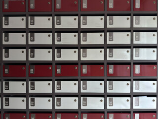 Rows of Red and White Apartment Mailboxes with Number Tags in Residential Building Lobby