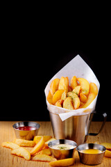 맛있게 튀겨진 웨지 감자 튀김과 다양한 소스들.