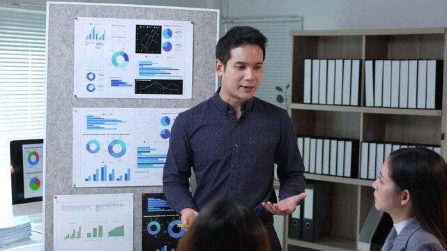Competent asian businessman manager presenting company marketing data analysis information to colleagues in meeting room, explaining charts and graphs showing company growth and success