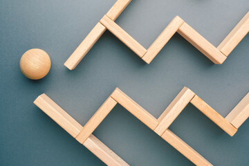 A wooden ball faces a zigzag maze built from blocks, symbolizing challenges, strategic thinking, and persistence on the journey toward goals and personal or business success