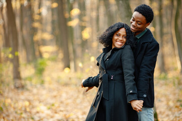 Loving black couple walking in park and enjoying autumn day