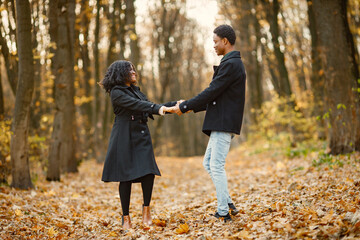Loving black couple walking in park and enjoying autumn day