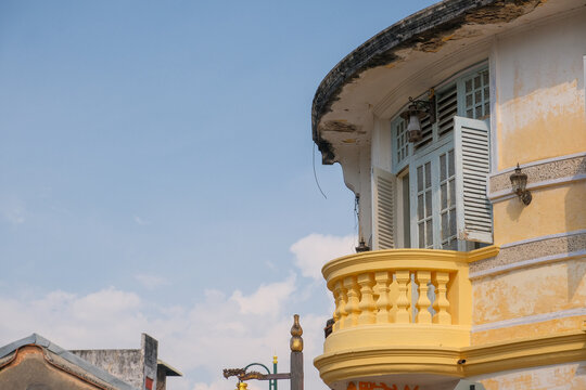 Weathered yellow colonial-style architecture balcony and shutter windows on a heritage building in George Town, Penang, Malaysia.