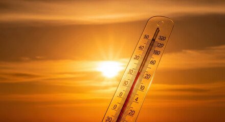 thermometer showing high temperature against intense summer sun and orange sky