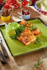 Salmon steak plated with grilled vegetables, bright daylight, overhead composition