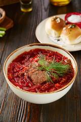 Venison borscht in rustic lighting, overhead composition with rich red broth and fresh dill garnish