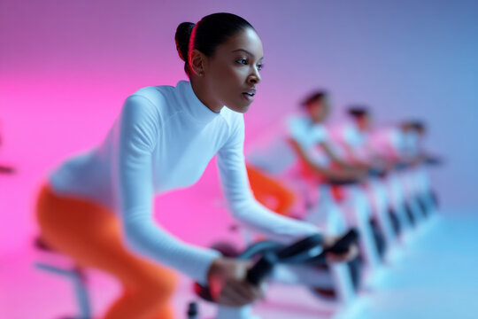 Athletic woman doing spinning in a modern gym with neon lights