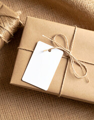 Kraft Paper Gift Box with Blank Label on Burlap Background.photo, commercial, eco, elegant, graphic, image, label, marketing, minimal, present, ribbon, sustainable, warm, branding,