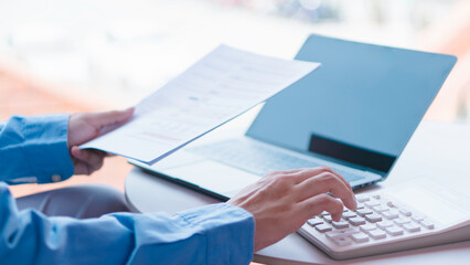 Financial management and expense calculation concept, professional analyzing financial reports and using calculator and laptop for budgeting.