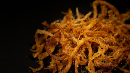 Crispy dried shredded pork isolated on black background. Closeup