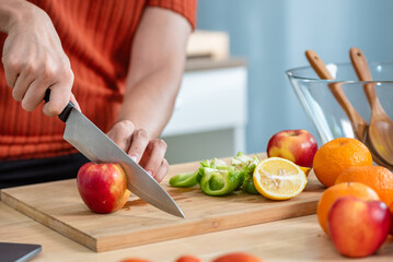 Hand chef knife cut and slice fresh Vegetables baby cos salad on wood board table .Make Salad Organic Vegetables mix lunch with green vegetables and fruit at kitchen table on wood cutting board.