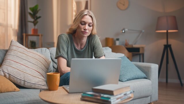Stressed depressed pretty woman working on laptop online at home. Sad tired beautiful female closing computer finishing work. Young attractive lady sitting on sofa in living room. Work stress concept.