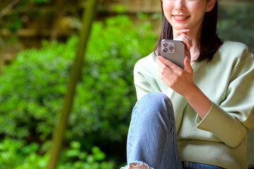 スマートフォンを手に微笑む女性の穏やかな暮らしと自然光あふれる空間