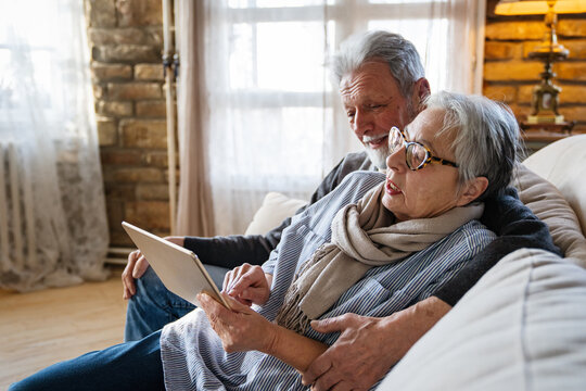 Elderly couple enjoying a tablet. Senior woman and man smiling, sharing technology.