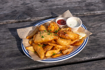 Fish and chips meal without soup served on rustic wood picnic table under natural light