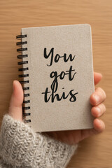 Close-up of hand holding notebook with handwritten motivational phrase You Got This. Message for mindset, productivity and personal development
