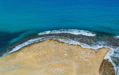 top view of Coastline with yellow sand meeting blue water