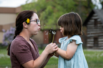 Obraz premium Dandelion fluff floats between mother and child mid-wish